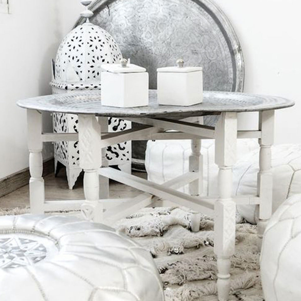 Stunning indoor space featuring a white Moroccan coffee table adorned with elegant white candles, surrounded by white leather poufs 