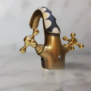 Back view of a Brass Bathroom Faucet with dual handles standing on a countertop with a marbel background 
