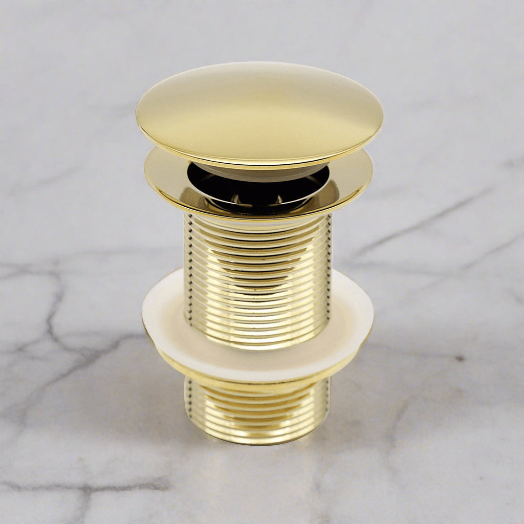 Brass popup drain with a white a white marble background 