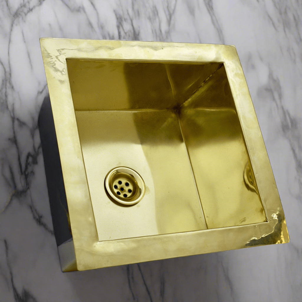 Front view of an ndermount Brass Kitchen Sink with white marble background 