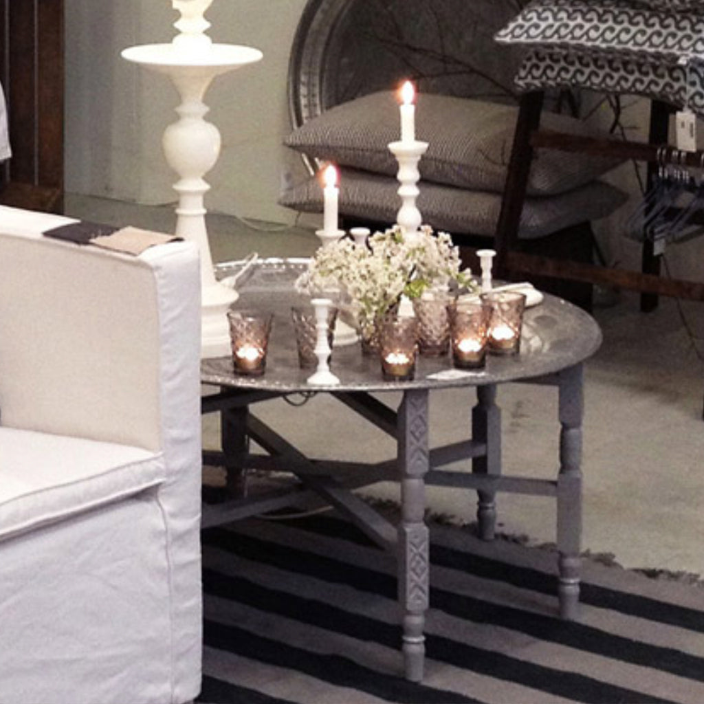 Moroccan tea table with glass candles, white candle holders, and a tree vase in a minimalist Berber-style living room