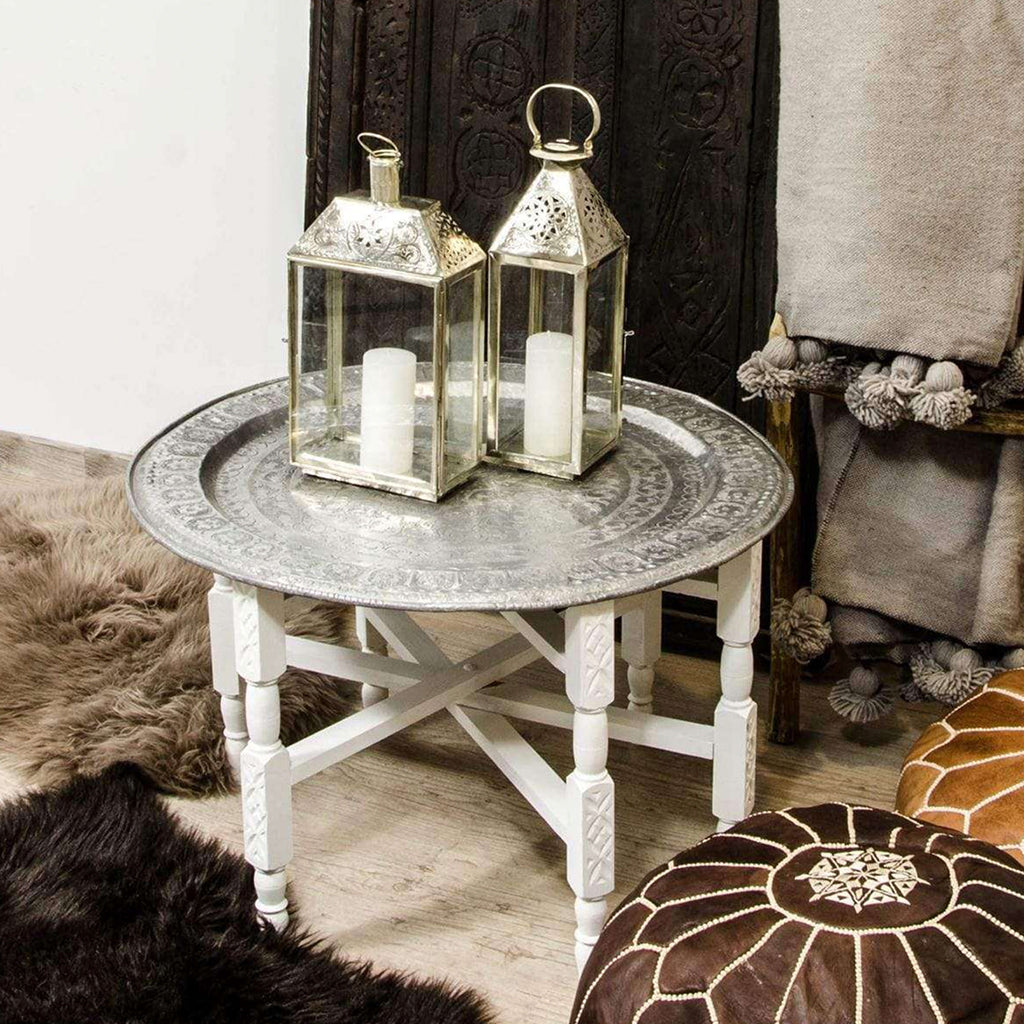 Moroccan-inspired living room with tea table, candles, blanket, ottomans, and vintage door against white wall