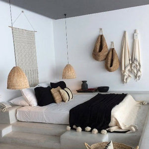 Black Moroccan Pom pom blanket on top of a bed with pillows in a bedroom with berber furniture - Moroccan Interior
