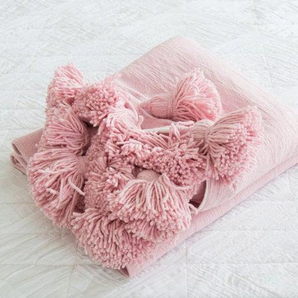 Moroccan Pompom Blanket in pink against a white background - Moroccan Interior