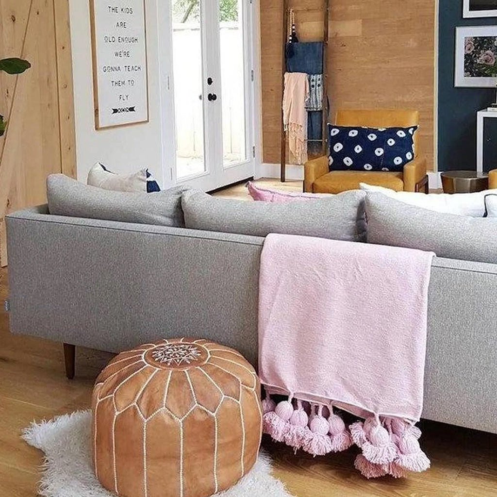 Moroccan Pompom Blanket in pink  draped over a gray couch in a living space with furniture - Moroccan Interior
