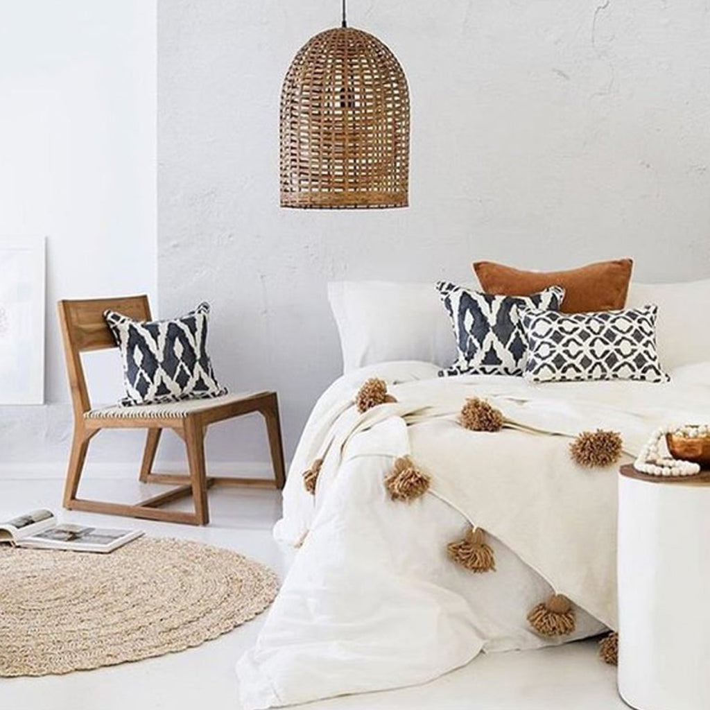 White and beige Moroccan Pom pom blanket on top of a bed with pillows in a bedroom with berber furniture - Moroccan Interior