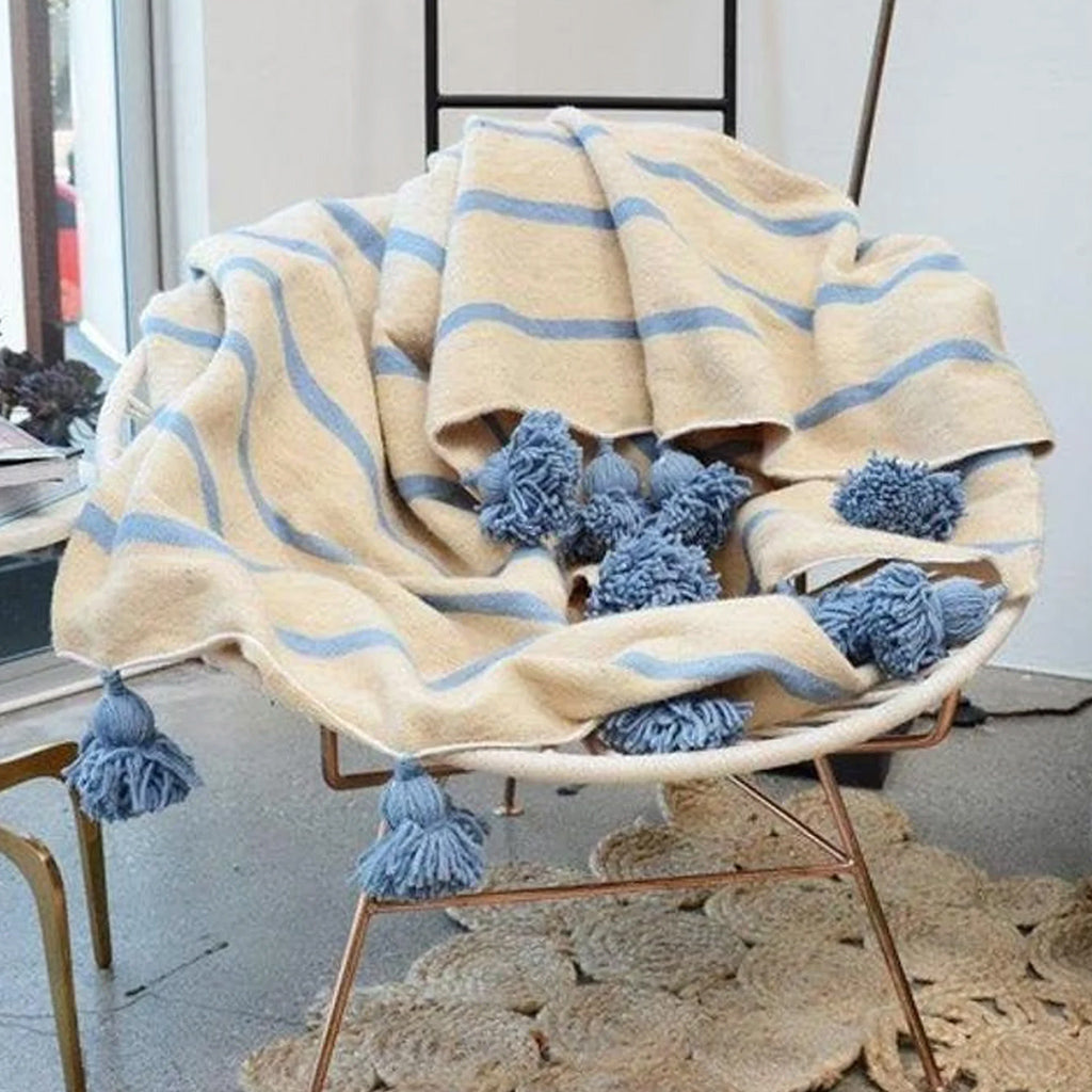Wool Moroccan Pompom Blanket in white and blue draped over a wooden chair - Moroccan Interior
