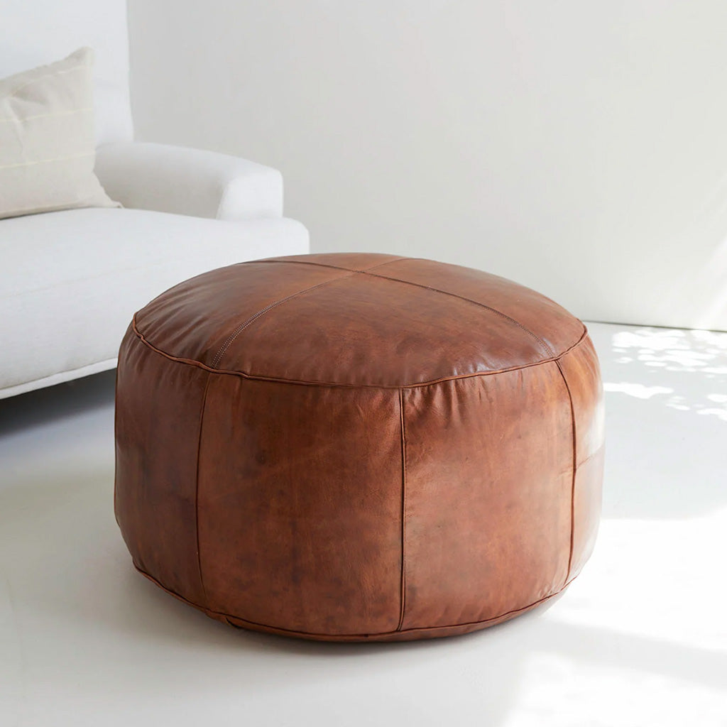 Round leather pouf near white sofa in bright living room - Moroccan Interior