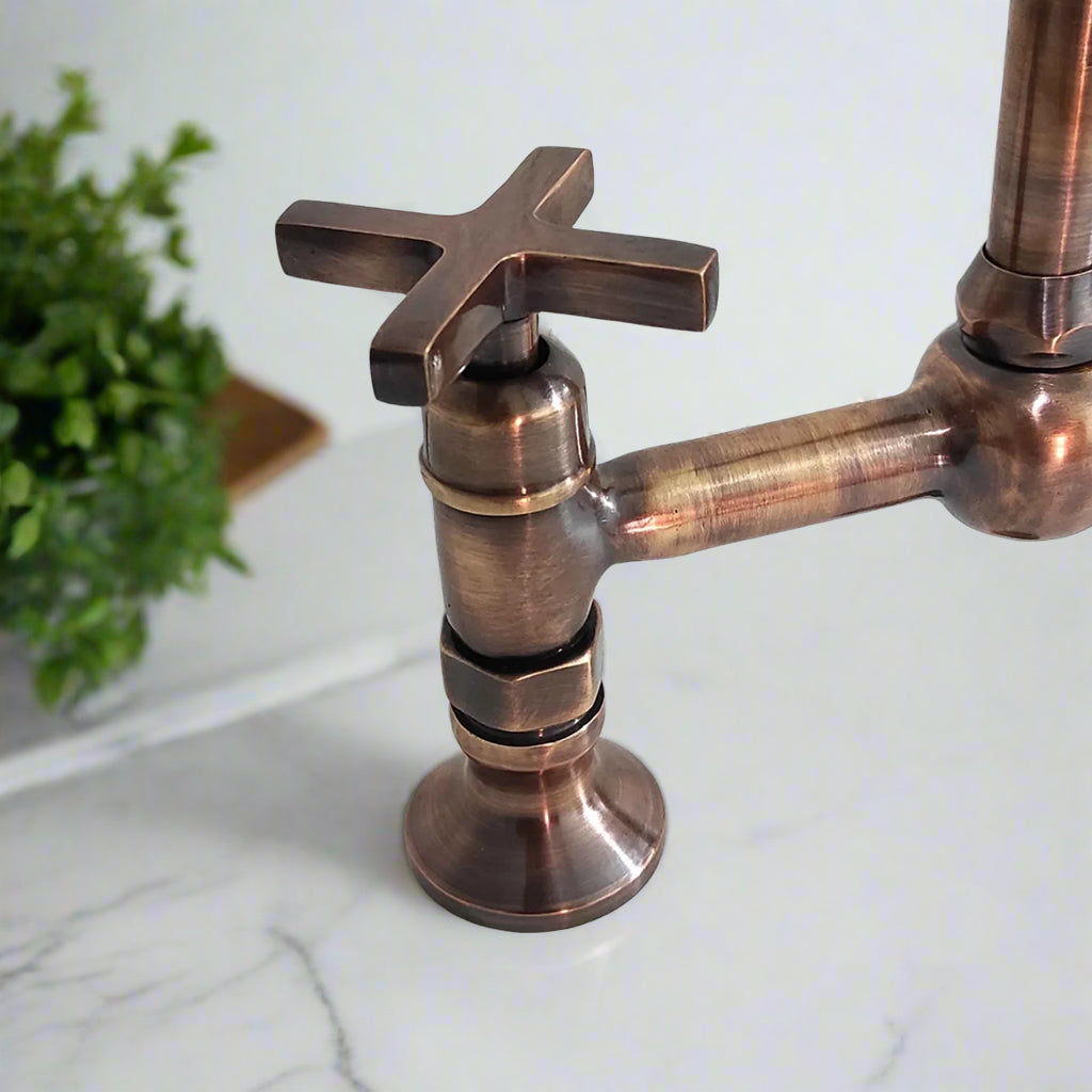 Close-up view of antique copper kitchen faucet with cross handle and traditional detailing