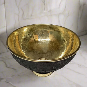 Top view of a handcrafted brass sink with a polished gold interior and rustic black outer texture