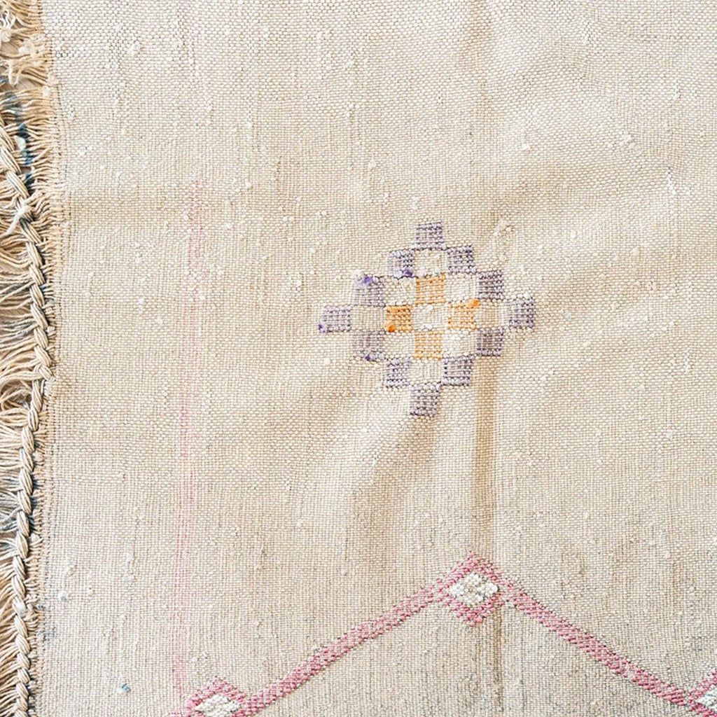 Detailed view of beige Moroccan cactus silk rug with geometric diamond embroidery in purple, yellow, and orange