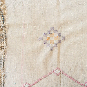 Detailed view of beige Moroccan cactus silk rug with geometric diamond embroidery in purple, yellow, and orange