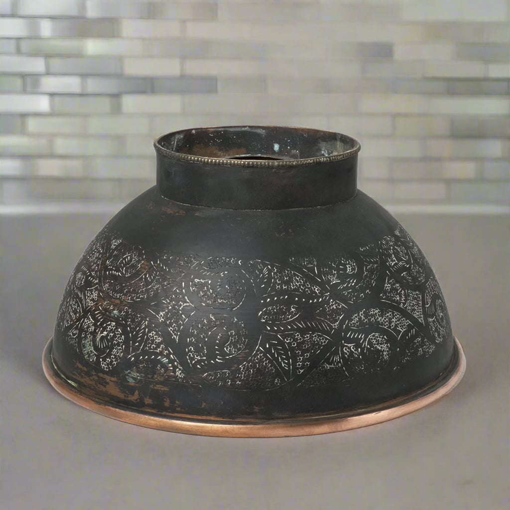Reversed view of hammered black copper vessel sink featuring an intricate engraved design