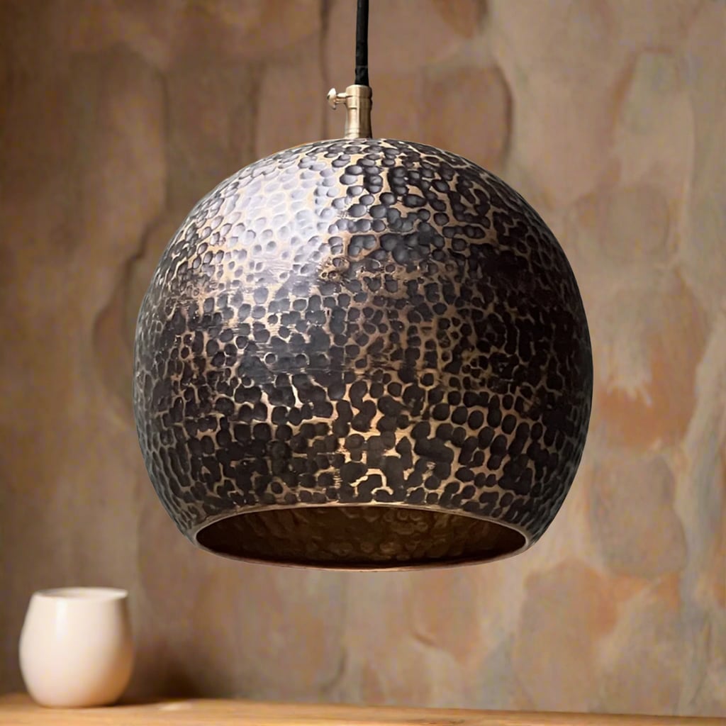 Black hammered copper pendant light with a rounded globe silhouette, displayed in a softly lit room with a natural-toned background