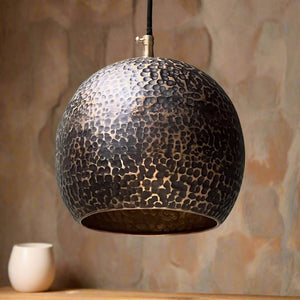 Black hammered copper pendant light with a rounded globe silhouette, displayed in a softly lit room with a natural-toned background