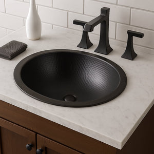 Black hammered copper sink installed in a bathroom vanity with a white marble countertop and matte black faucet set