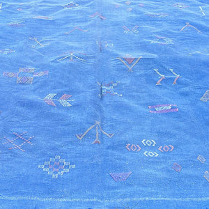 Close-up of a blue Moroccan sabra cactus silk rug featuring hand-embroidered Berber tribal motifs and colorful geometric patterns