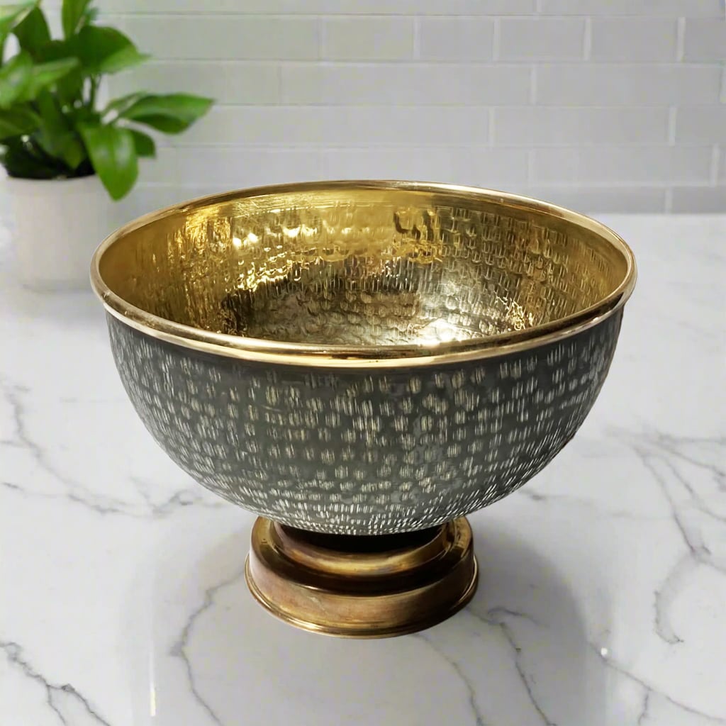 Hand-hammered brass bathroom sink with black textured exterior and polished gold interior, placed on a marble countertop