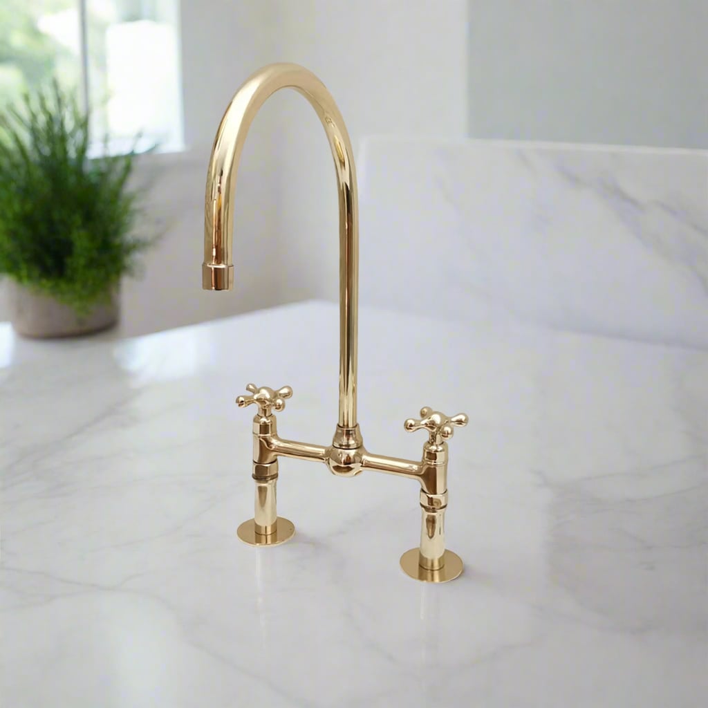 Classic brass bridge kitchen faucet with high arc gooseneck spout and cross handles, set on a marble countertop