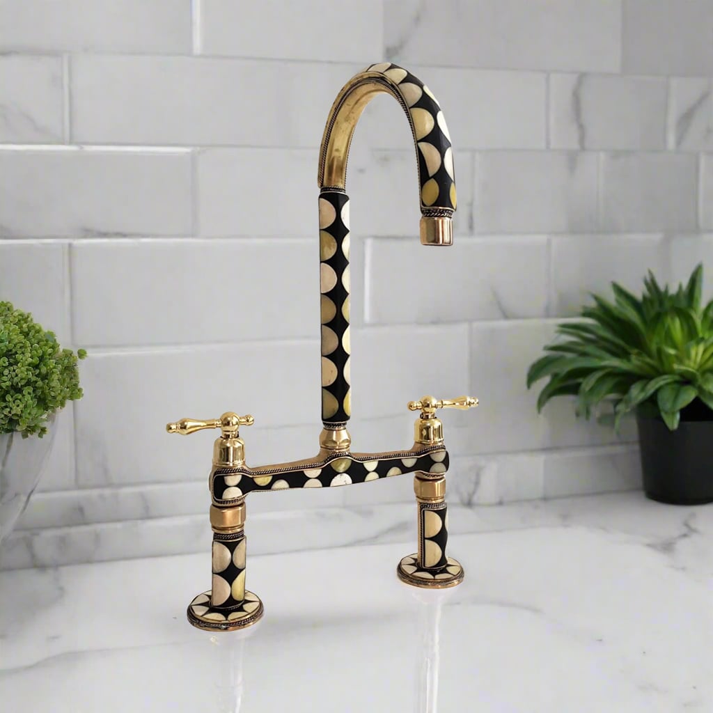 Brass kitchen faucet with geometric black and white inlay design and lever handles, mounted on a marble surface near subway tile backsplash