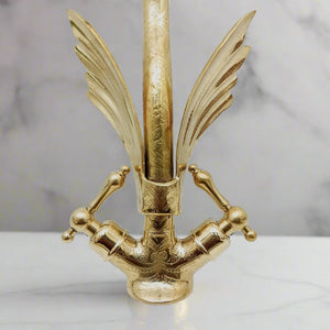 Close-up view of a brass swan-shaped faucet with detailed engravings and cross handles, showcasing artistic craftsmanship and vintage elegance