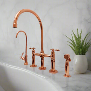 Copper kitchen bridge faucet set with a tall gooseneck spout, side sprayer, and filtered water tap on a marble countertop