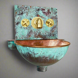 Hand-hammered copper wall-hung sink with verdigris patina and polished brass faucet, combining artisanal craftsmanship with timeless elegance