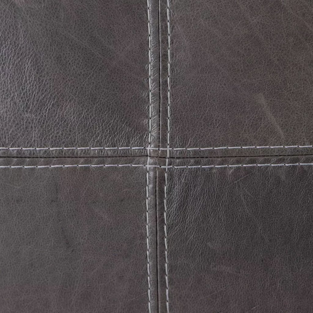 Close-up of the cross-stitching on a black leather headboard, highlighting the texture and craftsmanship of the full-grain leather