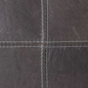 Close-up of the cross-stitching on a black leather headboard, highlighting the texture and craftsmanship of the full-grain leather