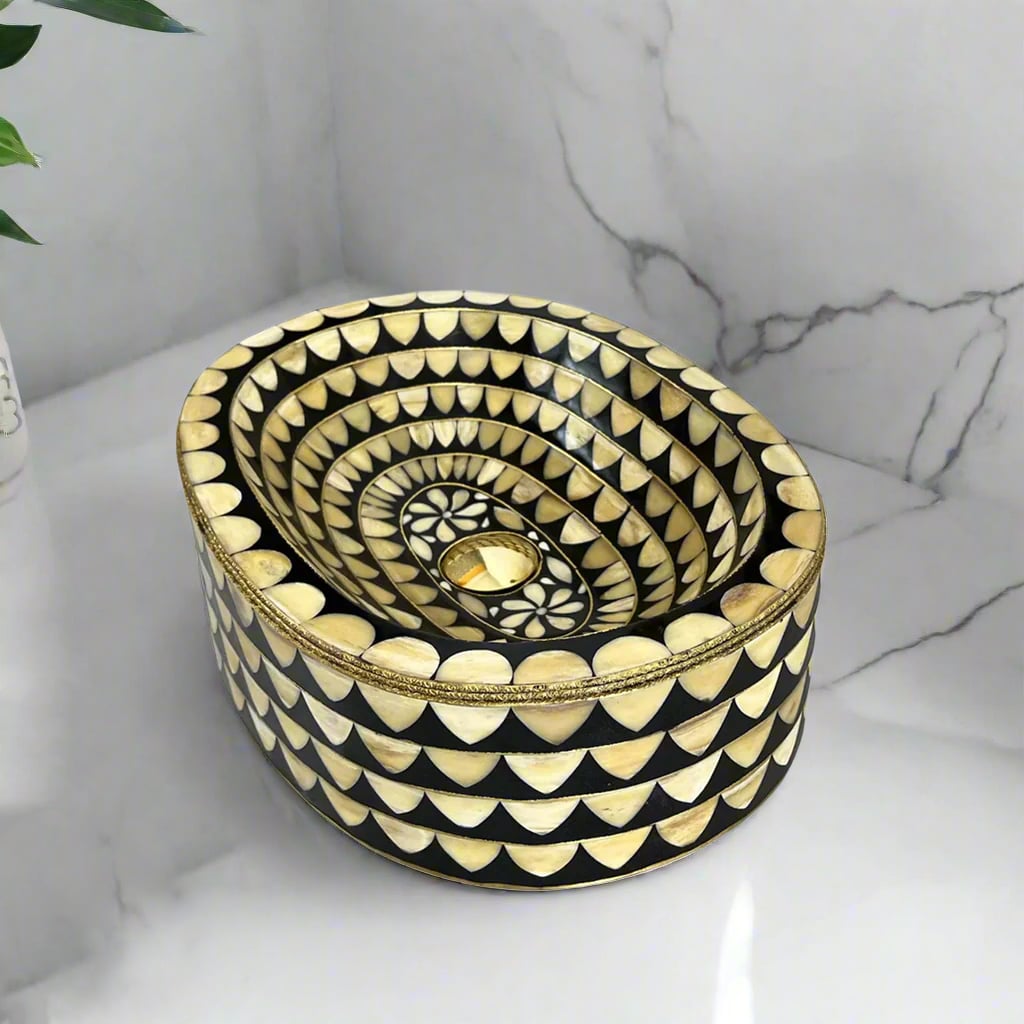 Top corner view of an oval inlay sink with floral center design and brass detailing