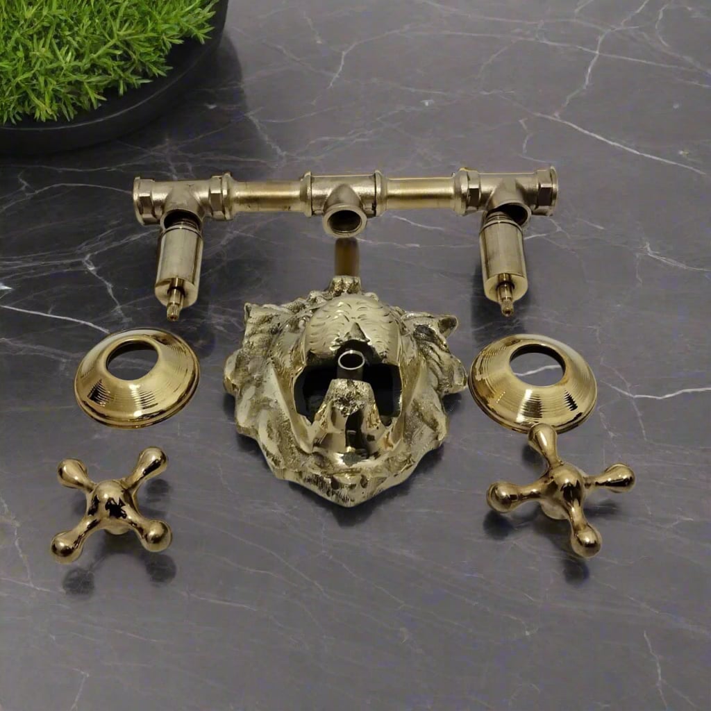 Disassembled brass lion head faucet kit with handles and fittings laid out on dark marble