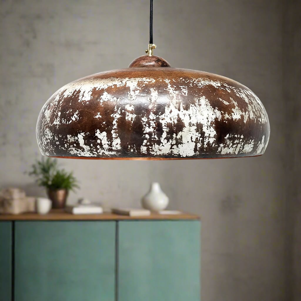 Close-up of a dome pendant light featuring a rustic brown and white weathered finish, set against a textured plaster wall