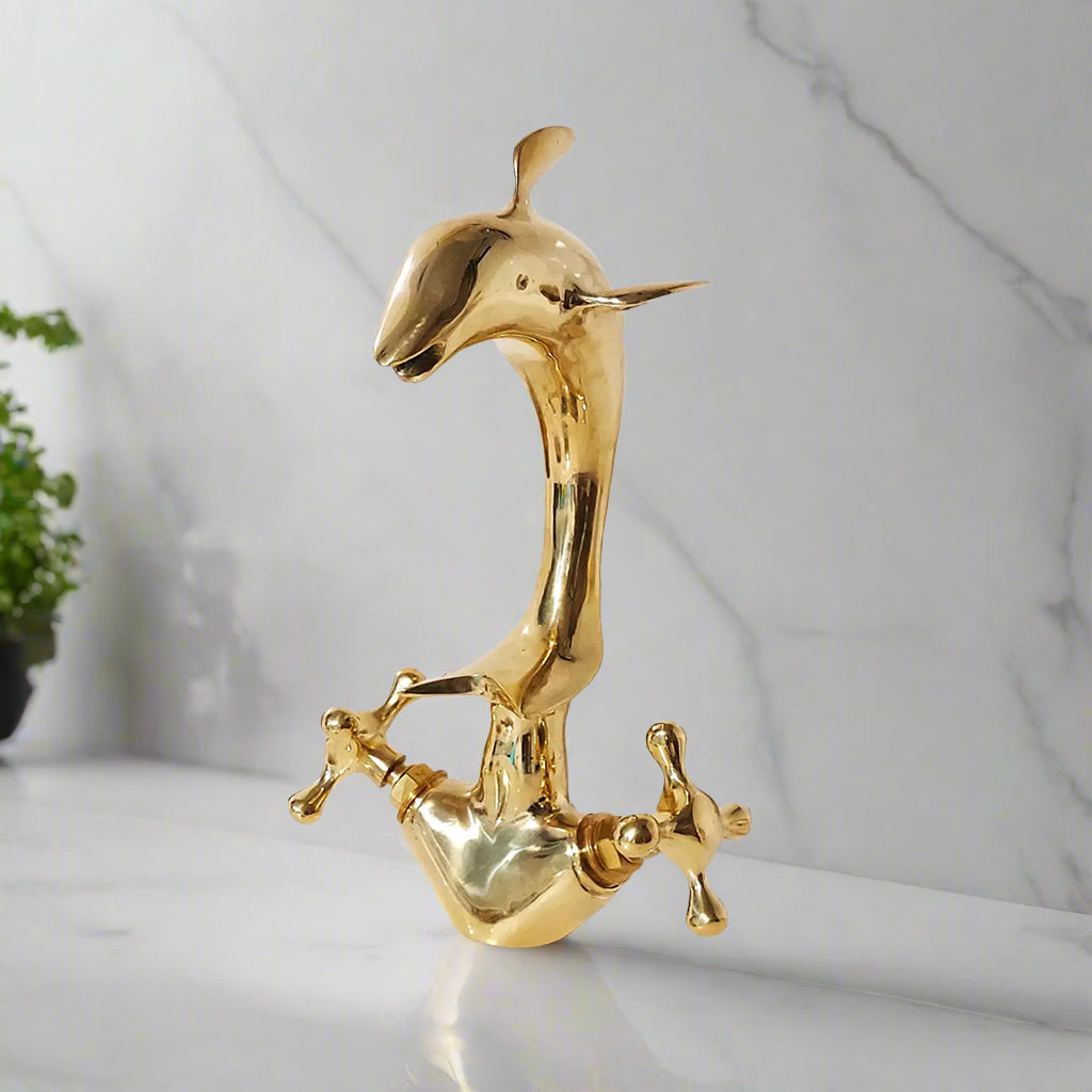 Dolphin-shaped brass faucet with polished smooth finish on marble background