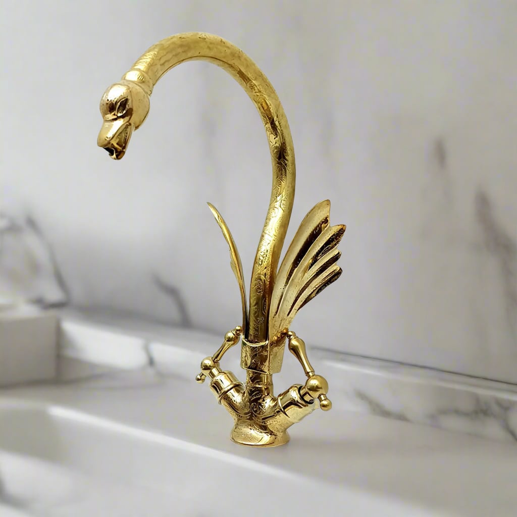 Decorative brass faucet with swan neck and intricate engravings, featuring knob handles and sculpted wings
