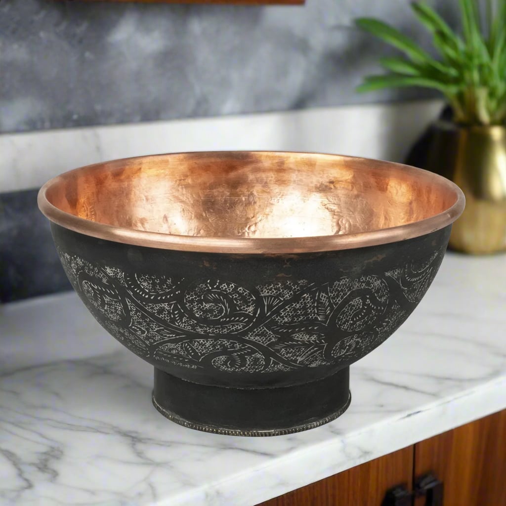Solid copper oval sink with embossed pattern and hammered texture, displayed on marble countertop