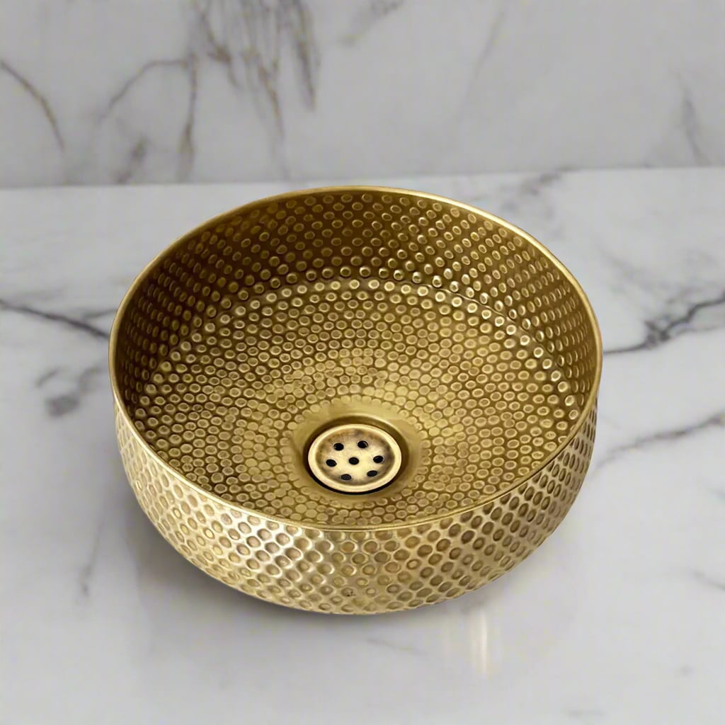 Top view of a hammered brass round basin with textured dot pattern, placed on a marble countertop