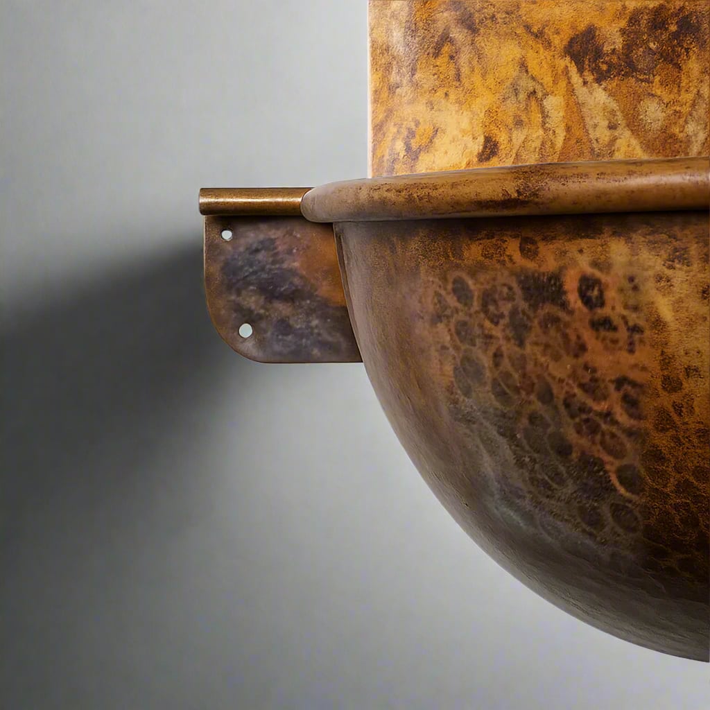 Close-up of a hammered copper wall-hung sink in golden-brown patina, showing detailed texture and sturdy wall-mount bracket