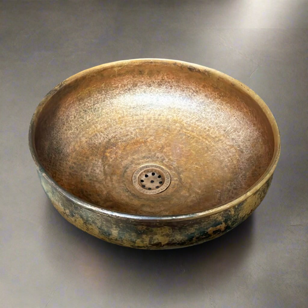 Hammered patina copper basin sink with a rustic finish and integrated drain, shown on a dark countertop