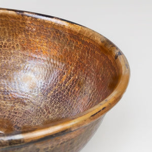 Close-up of a hand-hammered solid copper basin with rich patina and textured detailing, showcasing its artisanal craftsmanship