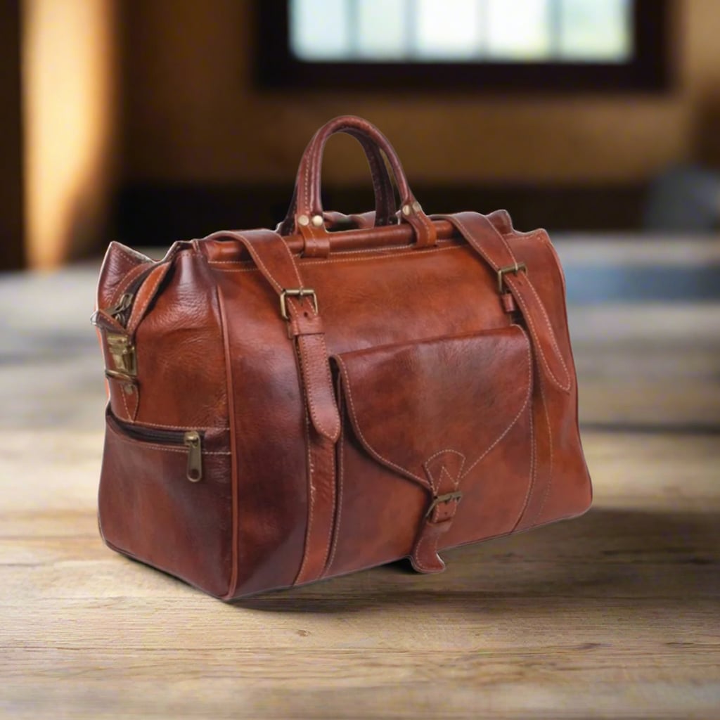 A three-quarter view of a handcrafted leather travel bag showcasing its elegant reddish-brown leather, a front flap pocket with buckle detail, and additional side pockets. Designed with reinforced straps, this bag is perfect for weekend getaways and daily use