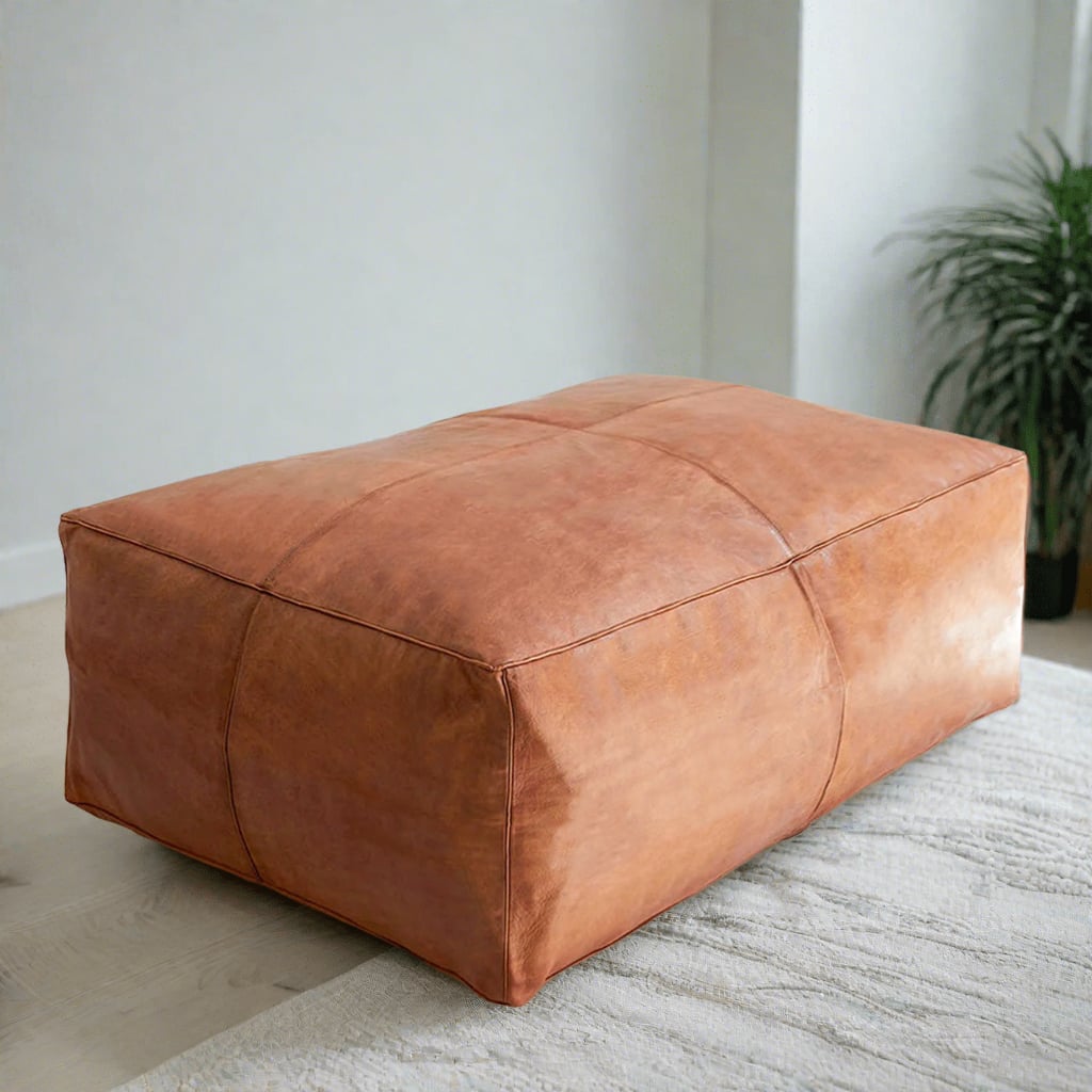 Handcrafted rectangular tan leather ottoman in a minimalist room setting, placed on a light rug with clean and simple decor that accentuates the ottoman's natural beauty.