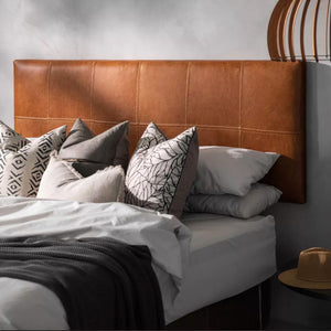 Side view of a Cozy bed with dark tan leather headboard, white bed linen, and decorative pillows - Moroccan Interior 
