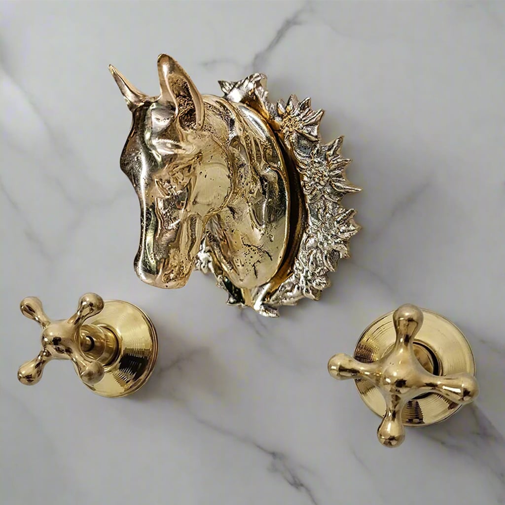 Elegant horse head brass faucet with intricate detailing, installed on a light marble wall, accompanied by two vintage-style brass cross handles