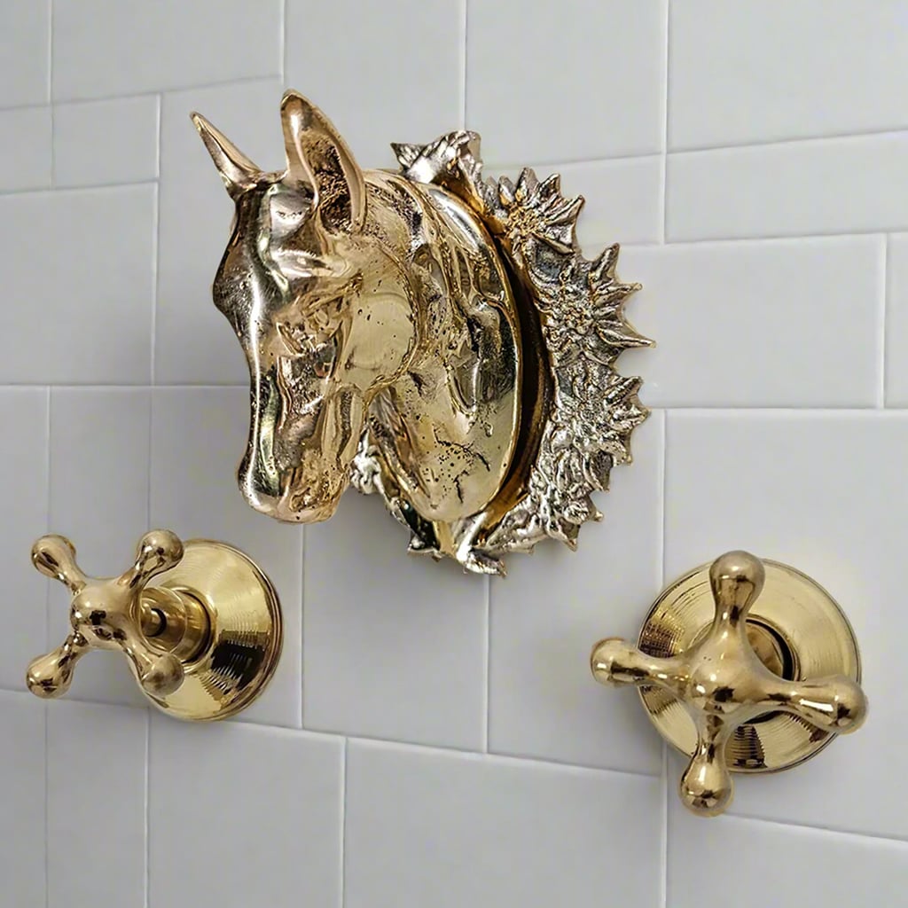 Luxurious wall-mounted faucet set with a gold horse head spout and matching brass handles, fixed against a white tiled background