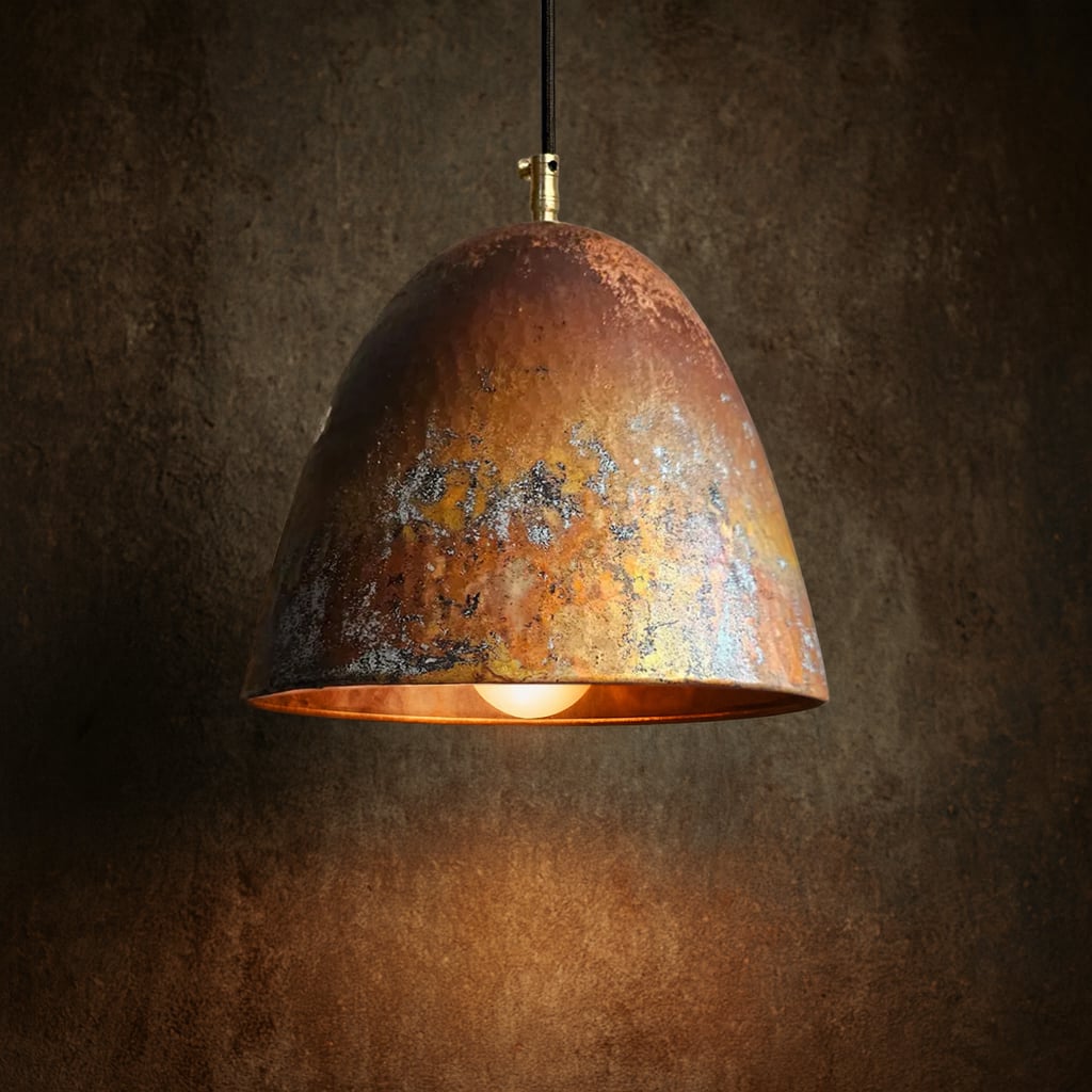 Single Moroccan pendant light with an aged copper patina, lit with warm glow against a textured dark brown wall