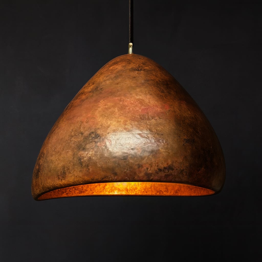 Handcrafted Moroccan pendant light with an organic dome shape, featuring a warm, richly textured hammered copper finish and a glowing golden interior, set against a dark background
