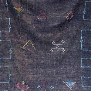Close-up of a black Moroccan sabra cactus silk rug with colorful geometric Berber motifs and embroidered tribal symbols