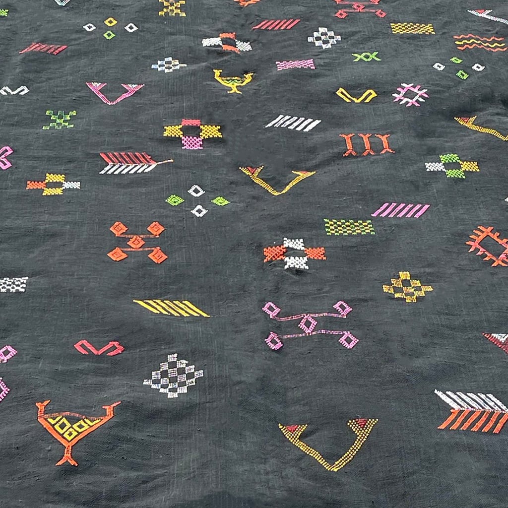 Close-up of a Moroccan sabra cactus silk rug in black, featuring colorful handwoven tribal embroidery with geometric and symbolic motifs