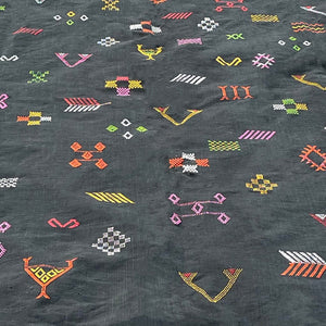 Close-up of a Moroccan sabra cactus silk rug in black, featuring colorful handwoven tribal embroidery with geometric and symbolic motifs