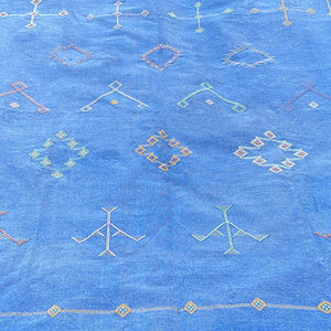 Blue Moroccan sabra cactus silk rug with detailed Berber tribal embroidery and geometric patterns, shown in a close-up view